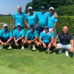 Équipe de golfeurs réunie sur un parcours verdoyant, portant des polos turquoise et des casquettes blanches. Le groupe est composé de neuf membres, dont certains sont accroupis et d'autres debout en arrière-plan. Cette image illustre un moment convivial et sportif, mettant en avant la camaraderie et l'esprit d'équipe lors d'une journée ensoleillée de golf.