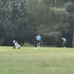 Sur un parcours de golf verdoyant, plusieurs golfeurs en tenue bleue s'entraînent sur le green. Deux chariots de golf sont visibles à proximité, tandis que les joueurs se concentrent sur leurs putts. En arrière-plan, des arbres luxuriants ajoutent à l'atmosphère paisible de ce cadre dédié au golf. Cette image illustre parfaitement la passion et la précision requises pour ce sport, tout en mettant en avant un environnement naturel propice à la pratique
