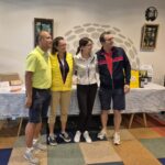 Quatre personnes posent ensemble dans un cadre convivial après un événement de golf. Elles se tiennent devant une table décorée avec des bouteilles de vin et des prix, témoignant de l'esprit de camaraderie et de compétition amicale. L'image illustre l'ambiance chaleureuse d'une remise de prix, avec des participants souriants et détendus, reflétant le plaisir du golf et des moments partagés.