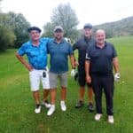 Quatre golfeurs posent sur un parcours verdoyant, entourés d'arbres. Ils portent des vêtements décontractés adaptés au golf, avec des gants et des clubs à la main. L'image capture une ambiance amicale et détendue, idéale pour illustrer des activités de loisirs en plein air. Cette scène met en avant le plaisir du golf et les interactions sociales entre amis.
