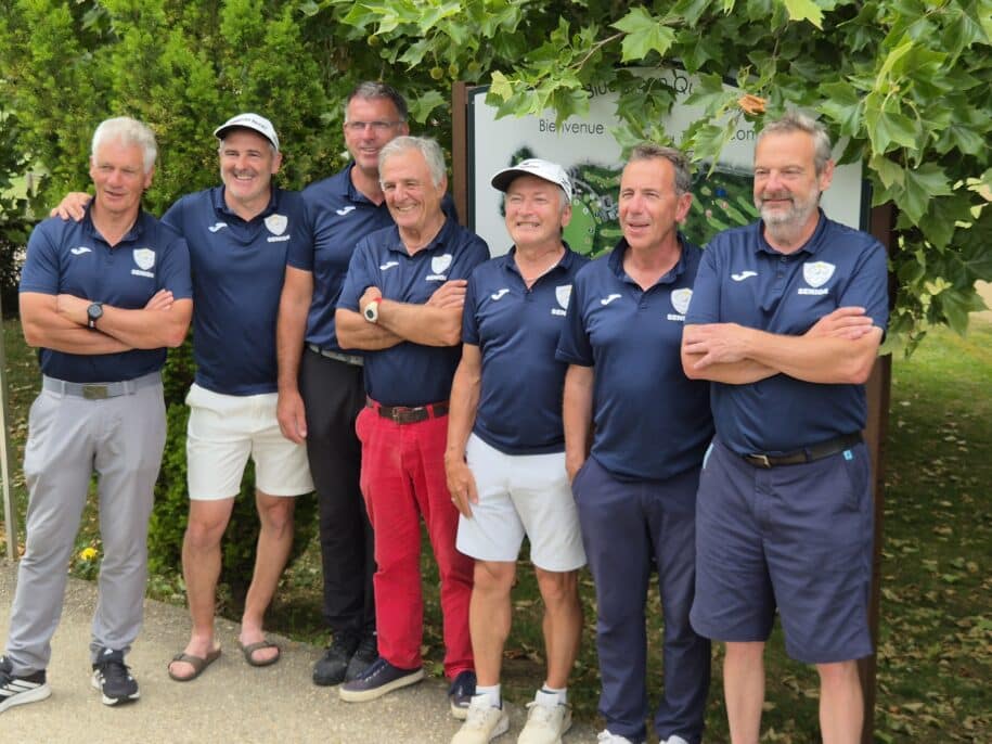 Groupe de sept hommes en tenue sportive, souriant et posant ensemble devant un mur de verdure. Ils portent des polos bleus et des shorts, représentant probablement une équipe ou un club sportif. L'image évoque un esprit d'équipe et de camaraderie, idéale pour illustrer des événements sportifs ou des rencontres amicales.