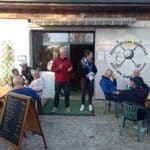 Réunion conviviale à l'Association Sportive Golf des Quatre Saisons, où des membres se rassemblent pour échanger et partager. On voit des participants assis autour de tables, certains écoutant attentivement des intervenants, tandis que d'autres discutent joyeusement. L'ambiance est chaleureuse et engageante, reflétant l'esprit communautaire du club. En arrière-plan, un tableau avec le menu du jour et le logo de l'association. Cette